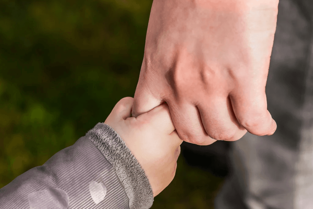 A child's hand holding an adult's finger
